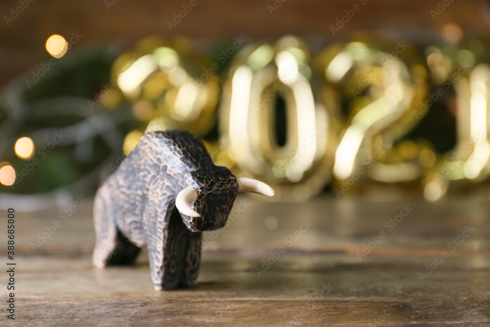 Figurine of bull as symbol of year 2021 on wooden table