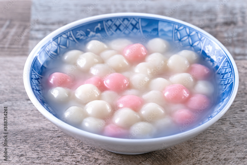 Close up of red and white tangyuan in blue bowl on wooden background for Winter solstice.