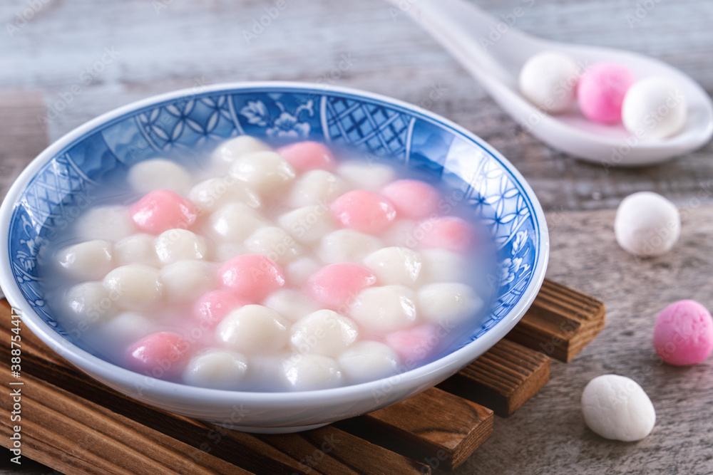 Close up of red and white tangyuan in blue bowl on wooden background for Winter solstice.