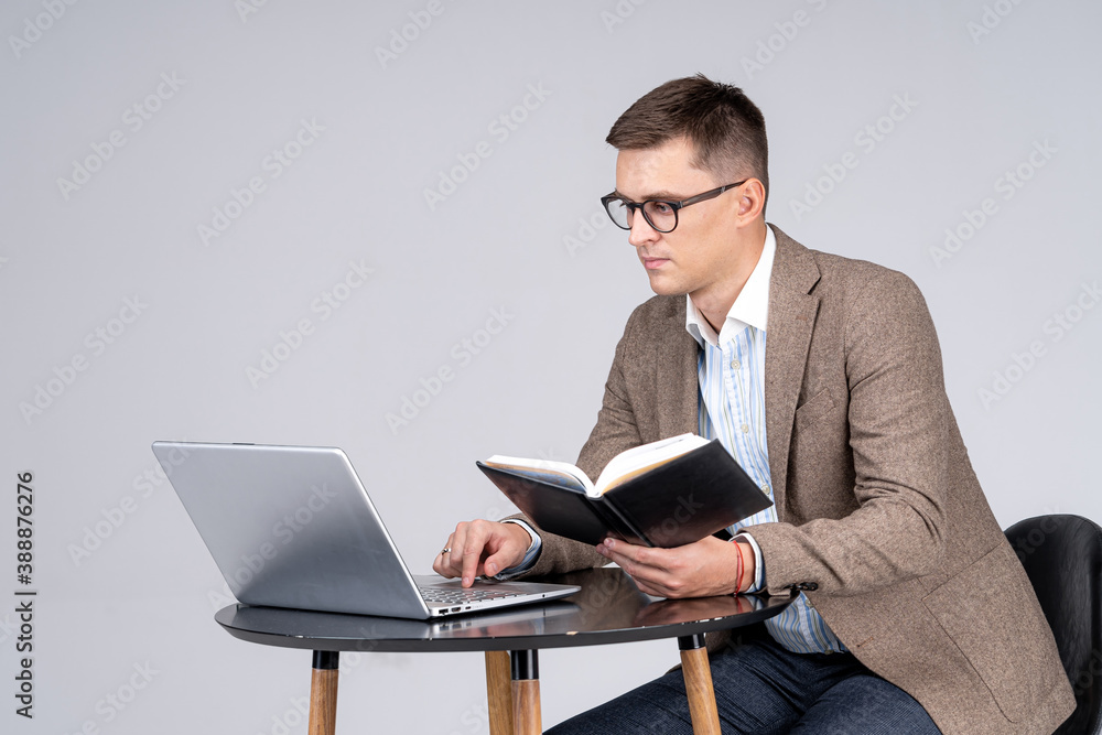 Male sales manager cheking schedule in notepad. Laptop on desk. Professional at work.