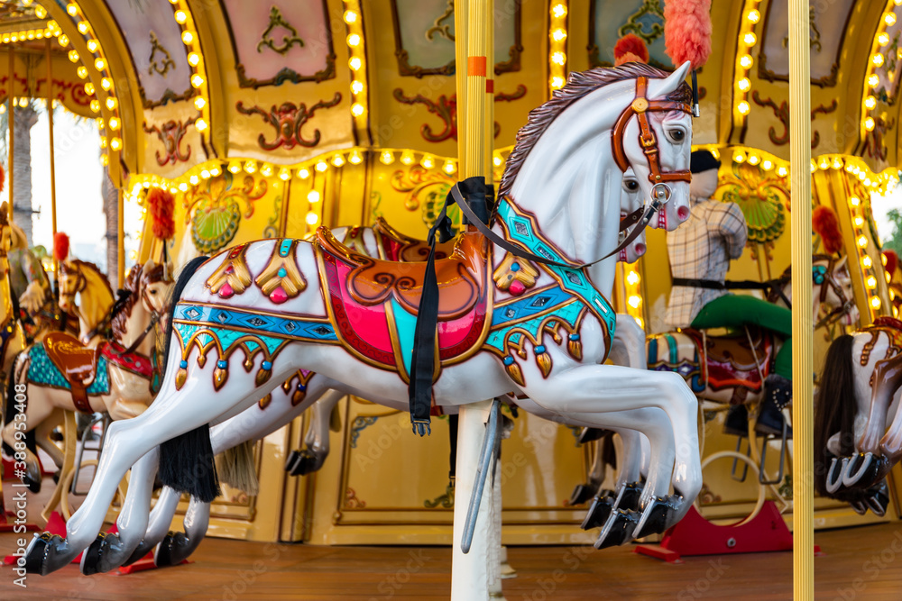 Colorful carousel horse on a vintage illuminated roundabout carousel (merry go round) in a park in D