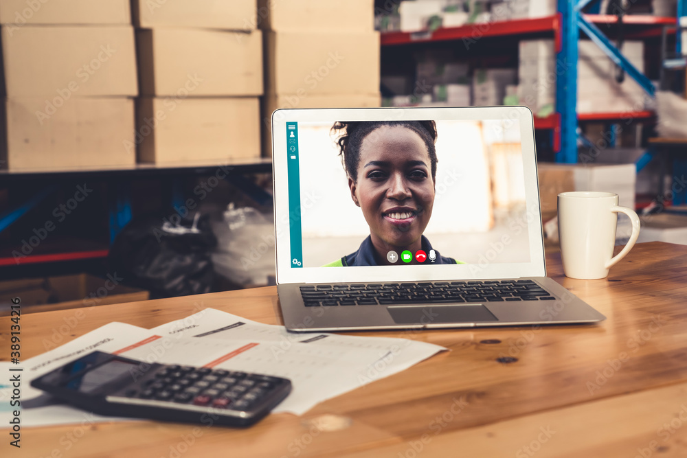 Warehouse staff talking on video call at computer screen in storage warehouse . Online software tech