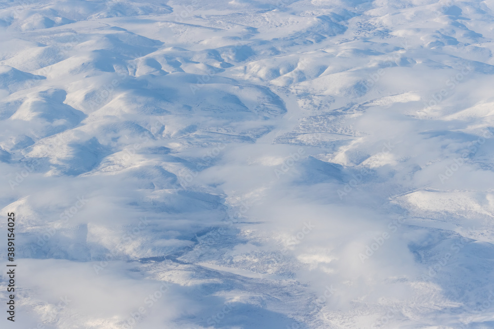 Aerial view of snow-capped mountains and clouds. Winter snowy mountain landscape. Icheghem Range, Ko