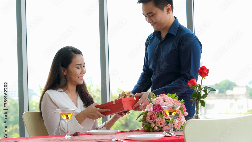 Romantic couple giving gift to lover at restaurant . Happy couple lifestyle .