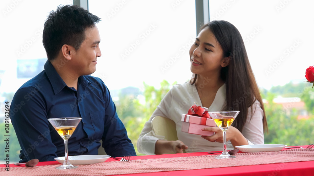 Romantic couple giving gift to lover at restaurant . Happy couple lifestyle .