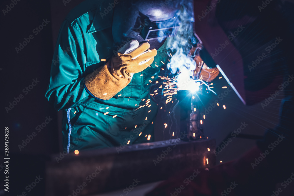 Metal welding steel works using electric arc welding machine to weld steel at factory. Metalwork man