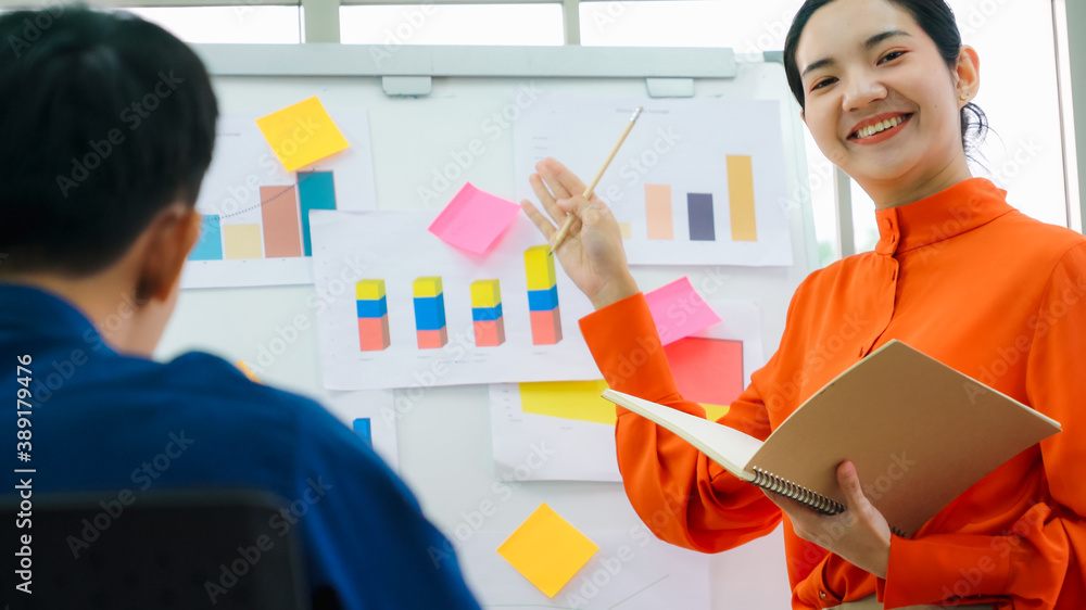 Young woman explains business data on white board in casual office room . The confident Asian busine