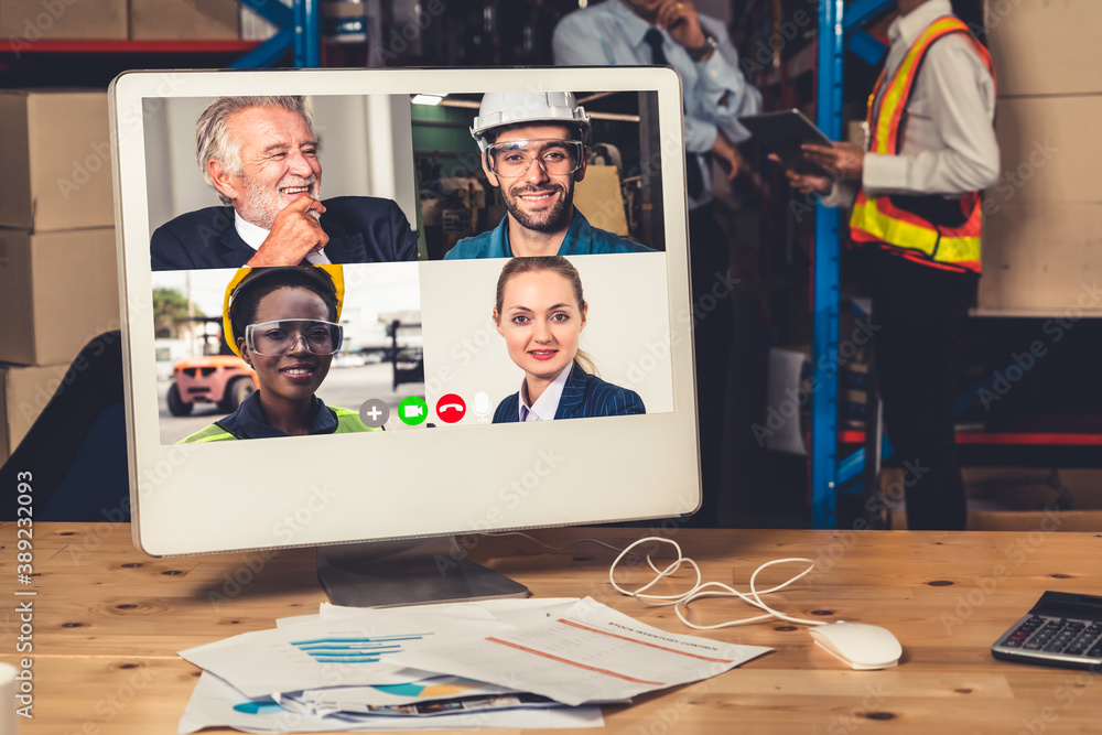 Warehouse staff talking on video call at computer screen in storage warehouse . Online software tech