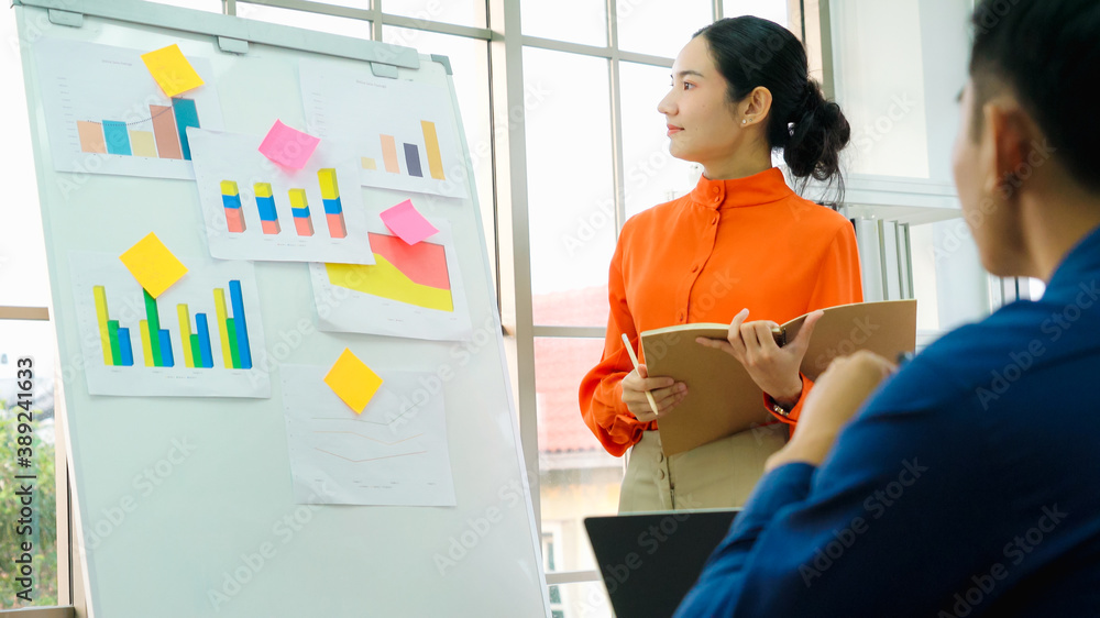 Young woman explains business data on white board in casual office room . The confident Asian busine