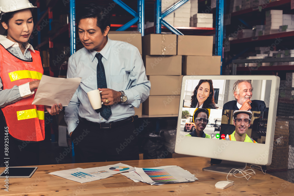 Warehouse staff talking on video call at computer screen in storage warehouse . Online software tech