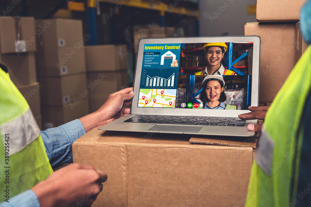 Warehouse staff talking on video call at computer screen in storage warehouse . Online software tech