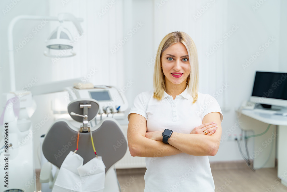 Female dentist is posing in modern stomatology clinic. Stomatological instrument and chair in the de