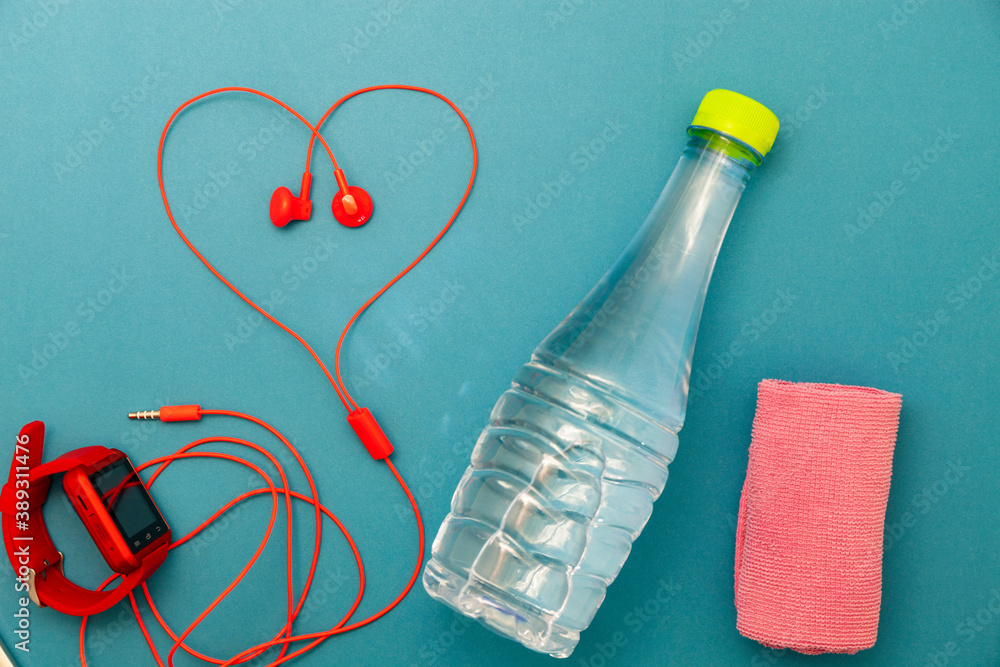 Close up of water bottle,watch and red earphones ,towel cloth on green background,fitness background