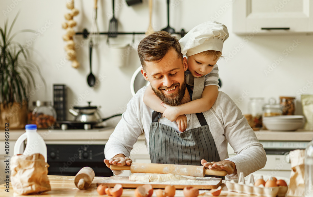 Cheerful man with little son making pastry at home.