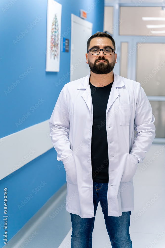 Doctor portrait on hospital corridor background. Doctor portrait in scrubs. Bearded doctor.