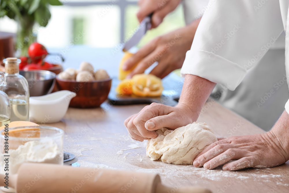 Female chef making dough in kitchen, closeup