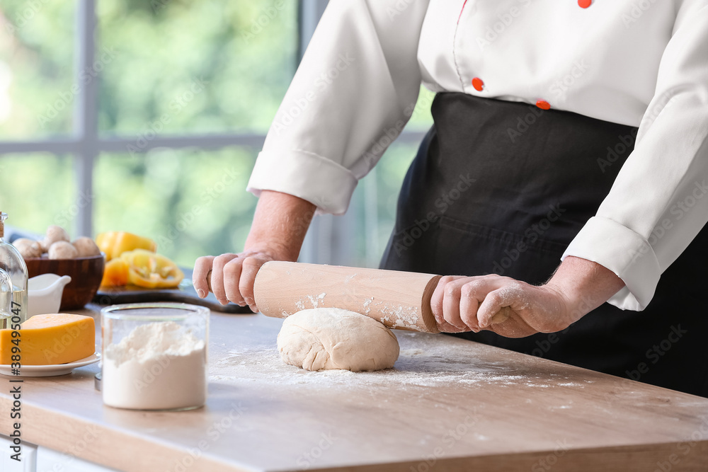 Female chef making dough in kitchen