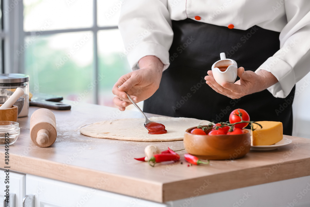 Mature female chef making tasty pizza in kitchen