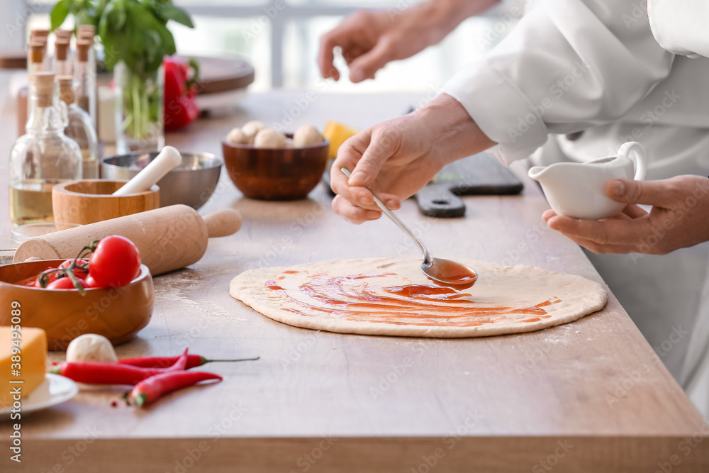 Chefs cooking tasty pizza in kitchen