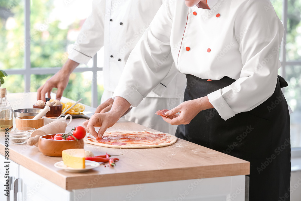 Chefs cooking tasty pizza in kitchen