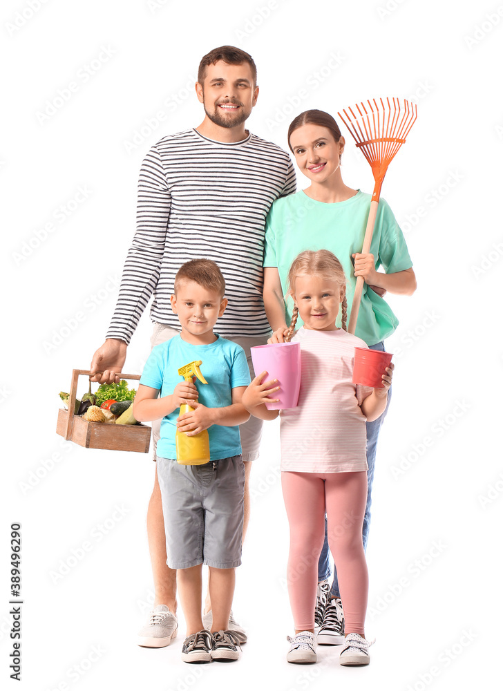 Young family with gardening supplies and harvest on white background