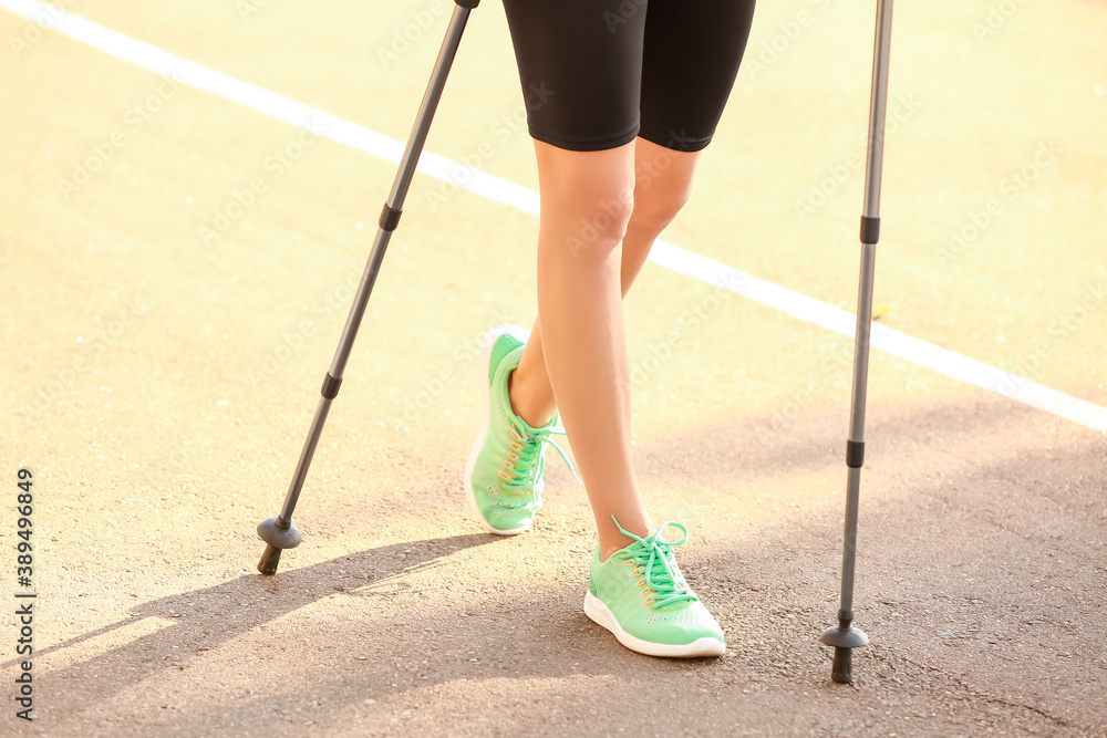 Young woman training with walking poles outdoors