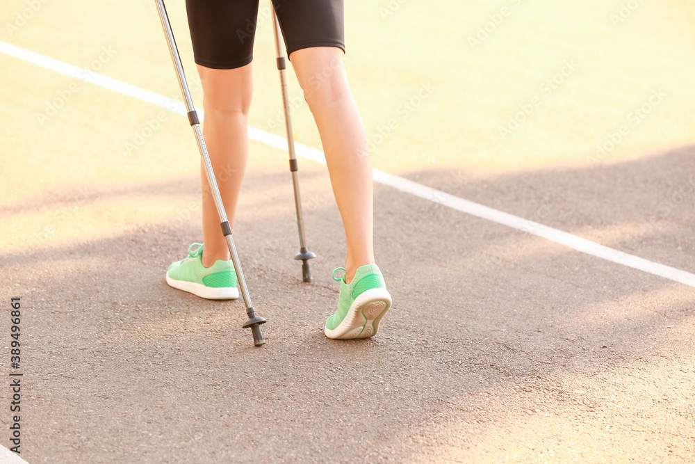 Young woman training with walking poles outdoors