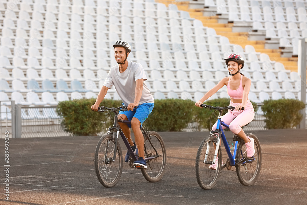 Sporty young couple riding bicycles at the stadium