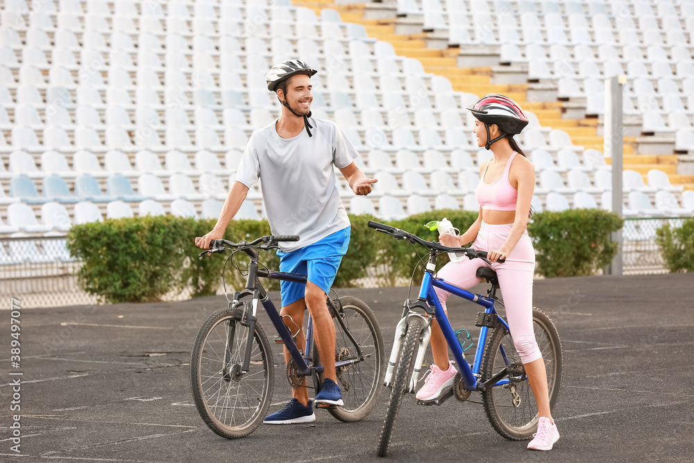 Sporty cyclists drinking water at the stadium