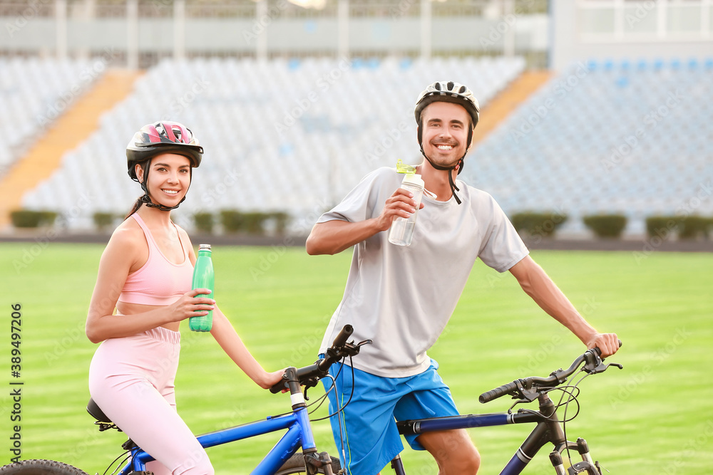 Sporty young cyclists drinking water at the stadium