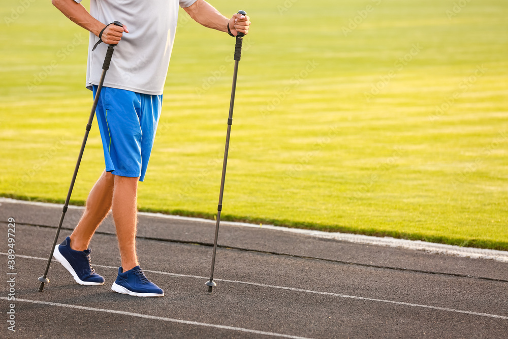 Young man training with walking poles at the stadium