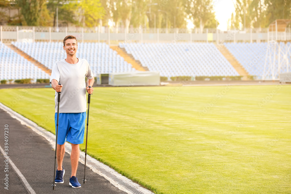 Young man training with walking poles at the stadium