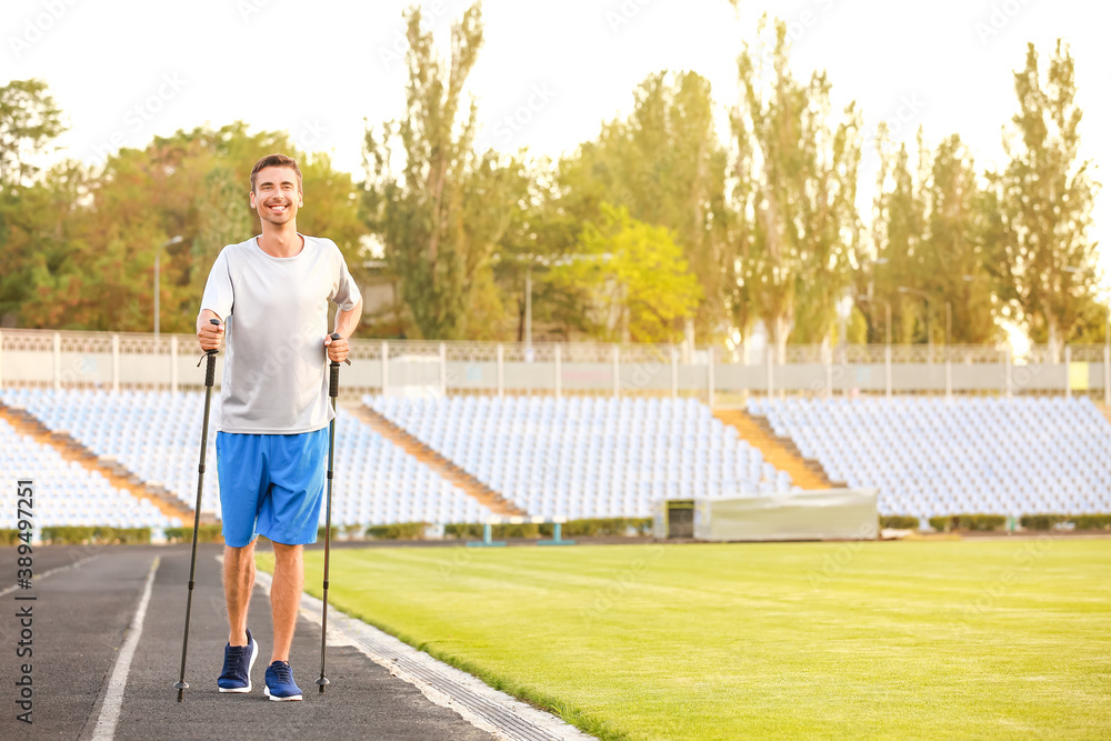 Young man training with walking poles at the stadium