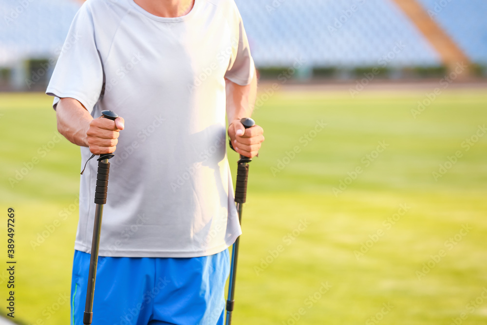 Young man training with walking poles at the stadium