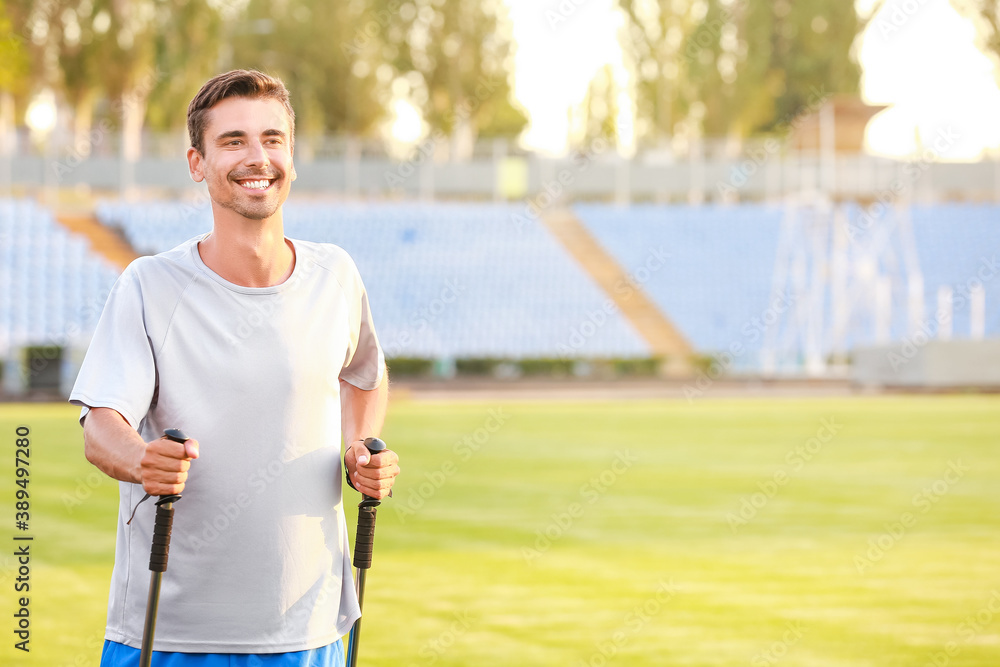 Young man training with walking poles at the stadium