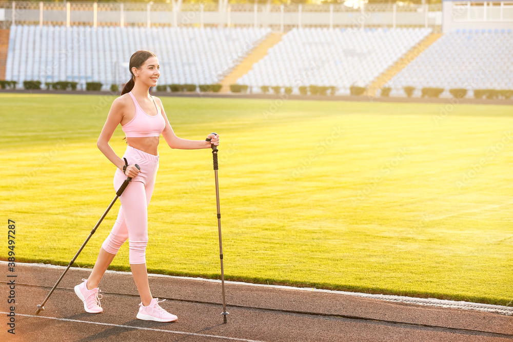 Young woman training with walking poles at the stadium