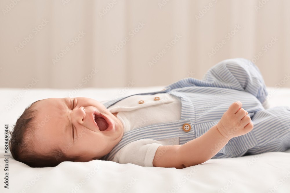 Cute little baby lying on bed at home