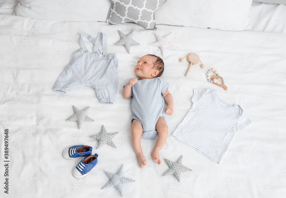 Cute little baby with clothes and accessories lying on bed, top view