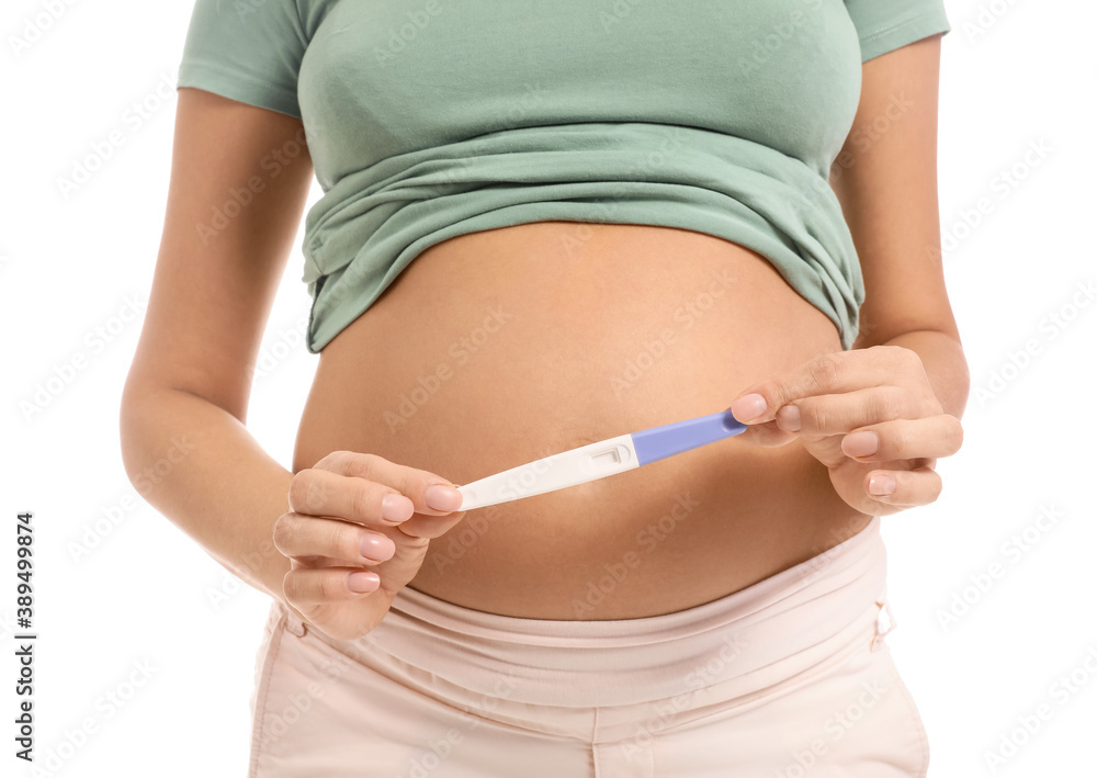 Beautiful pregnant woman with test on white background, closeup