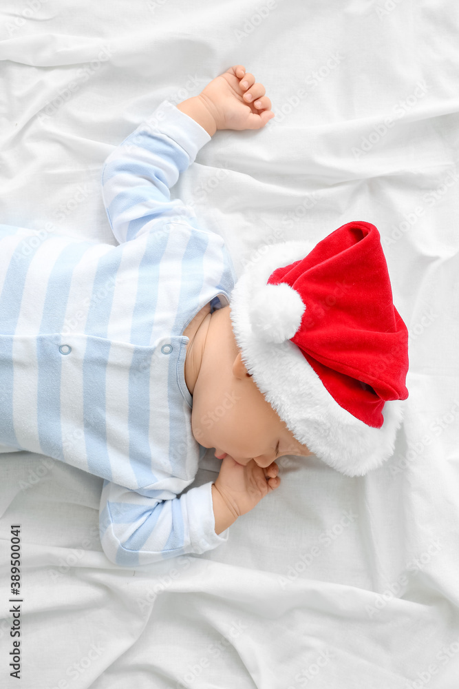 Cute little baby in Santa hat lying on bed