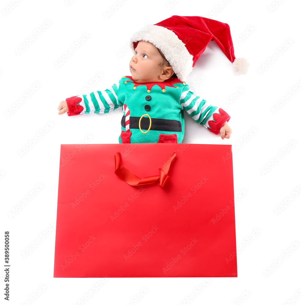 Cute little baby in Santa hat and with shopping bag on white background