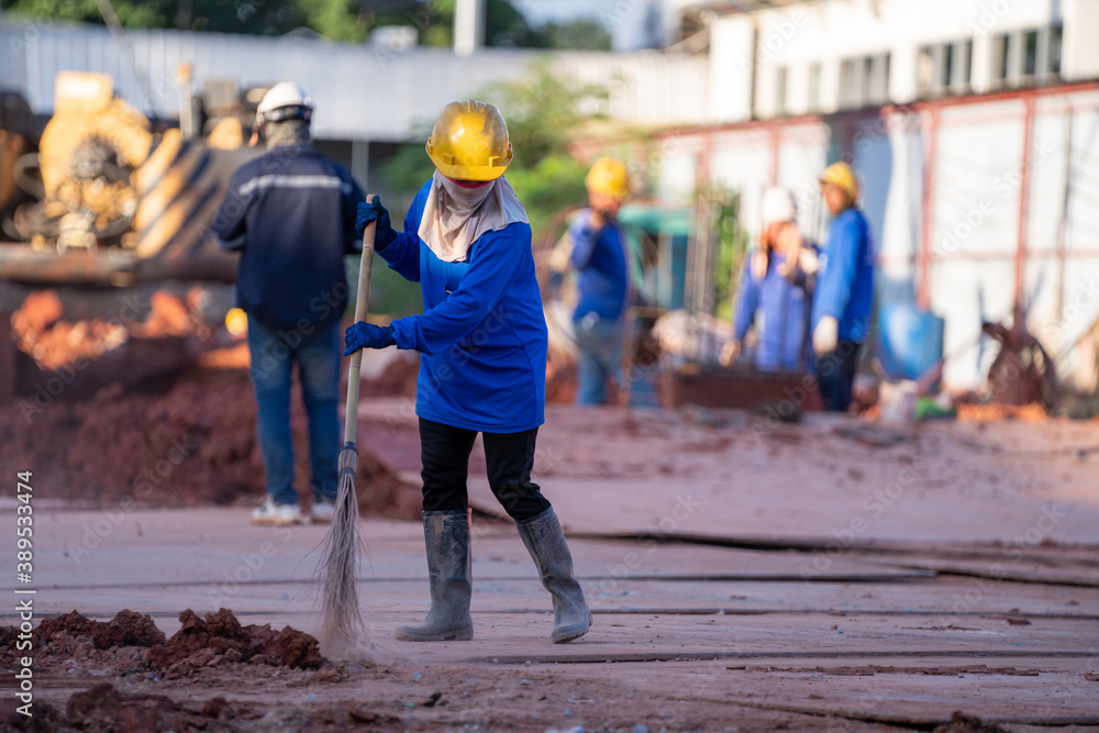 Construction worker sweepers soil debris with brush broom In the construction site