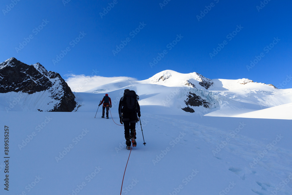 Rope team mountaineering with crampons on glacier Taschachferner towards Wildspitze and mountain sno