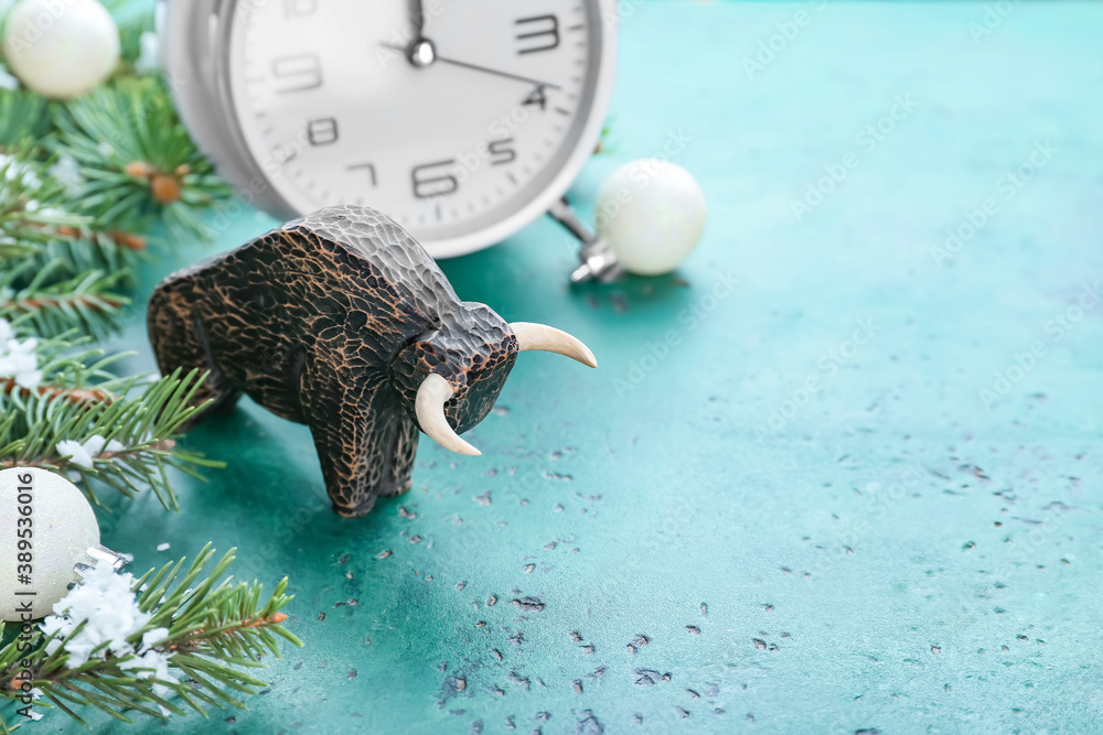 Figurine of bull, clock and New Year decor on color background