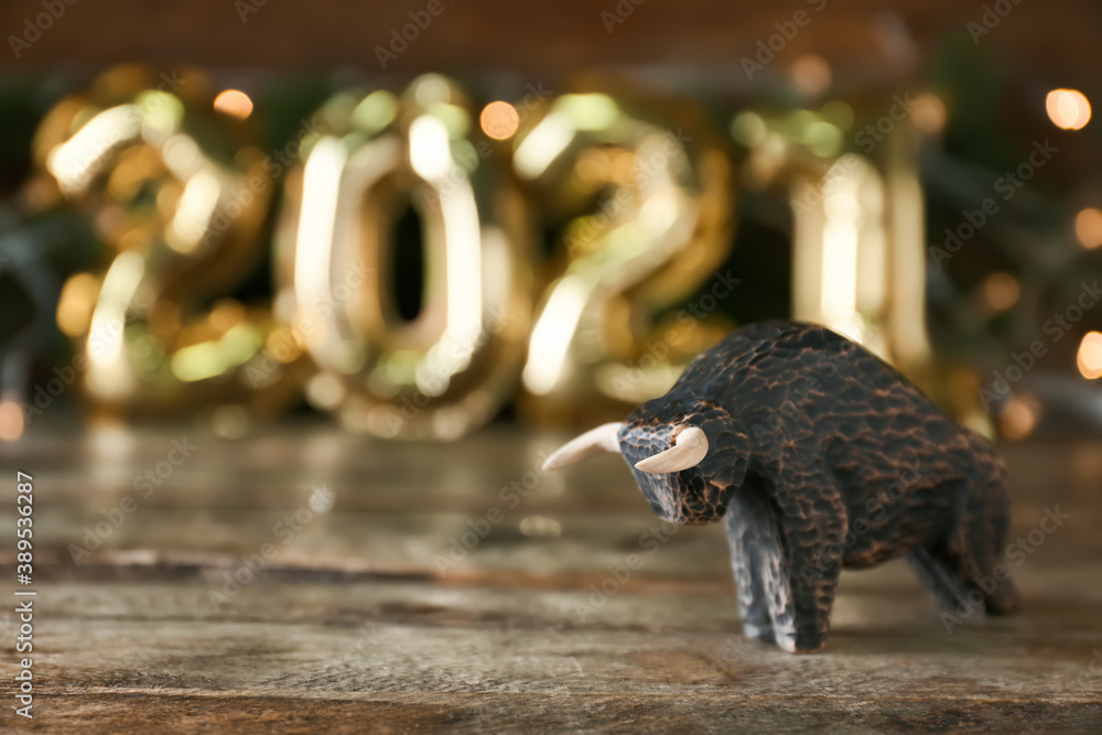 Figurine of bull as symbol of year 2021 on wooden table