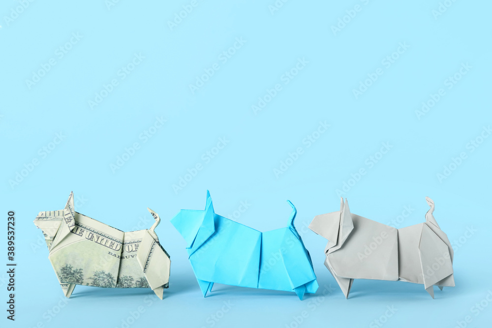 Origami bulls as symbol of year 2021 on color background