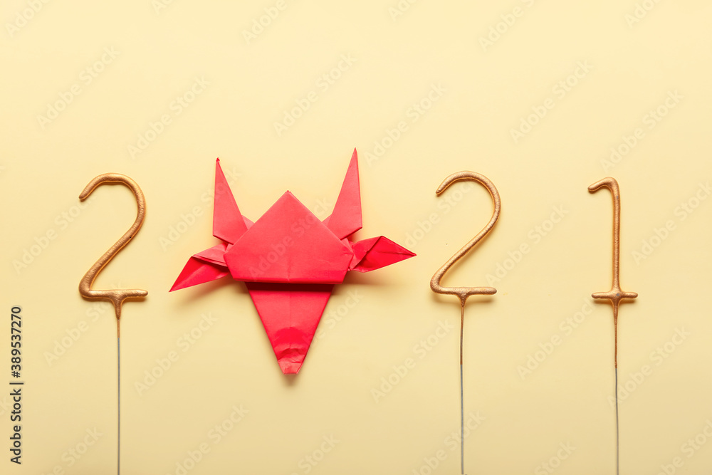 Figure 2021 with origami bull as symbol of the year on color background