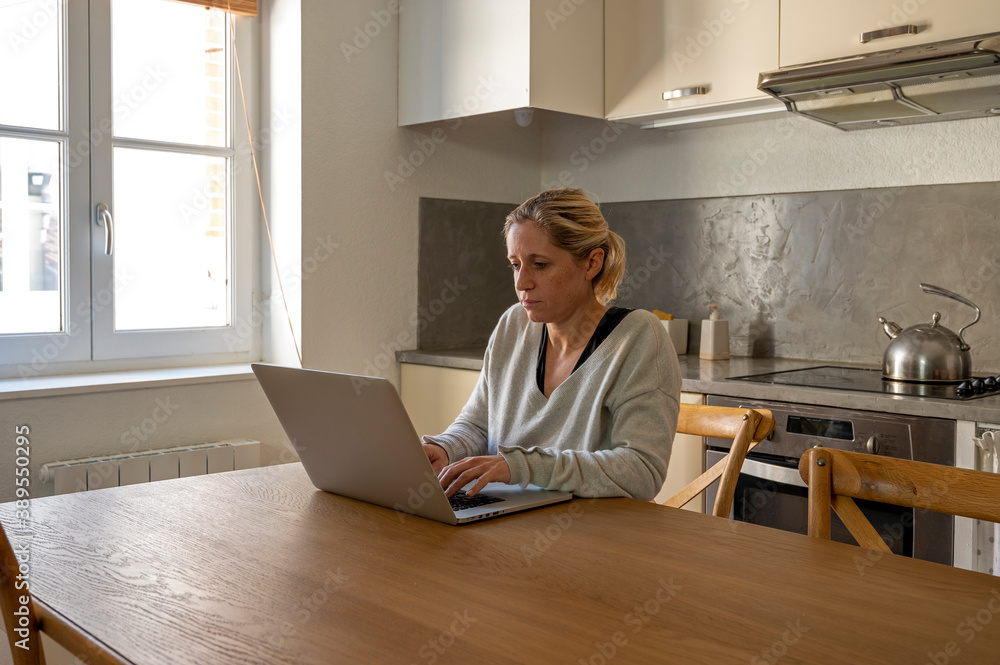 Femme dans sa cuisine en télétravail devant son ordinateur