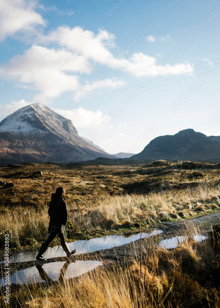 Woman walking on a road in Glen Etive, Scotland