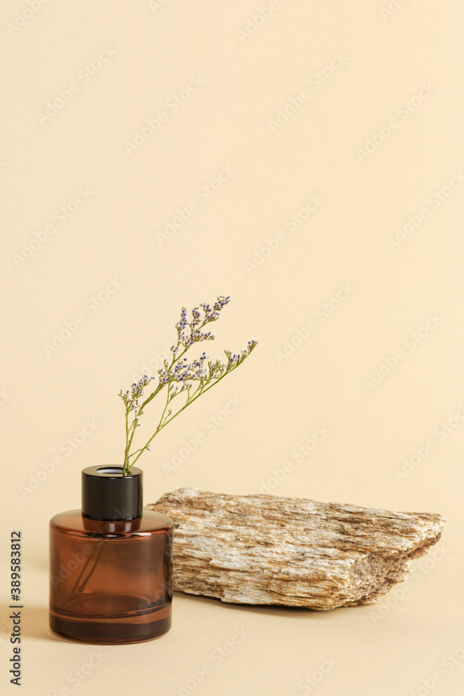 Dried grass flower in a brown bottle by a stone